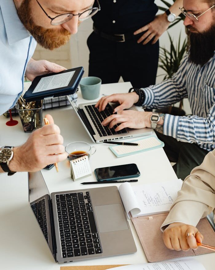 Teamwork in action with technology, papers, and collaboration at a dynamic office desk.