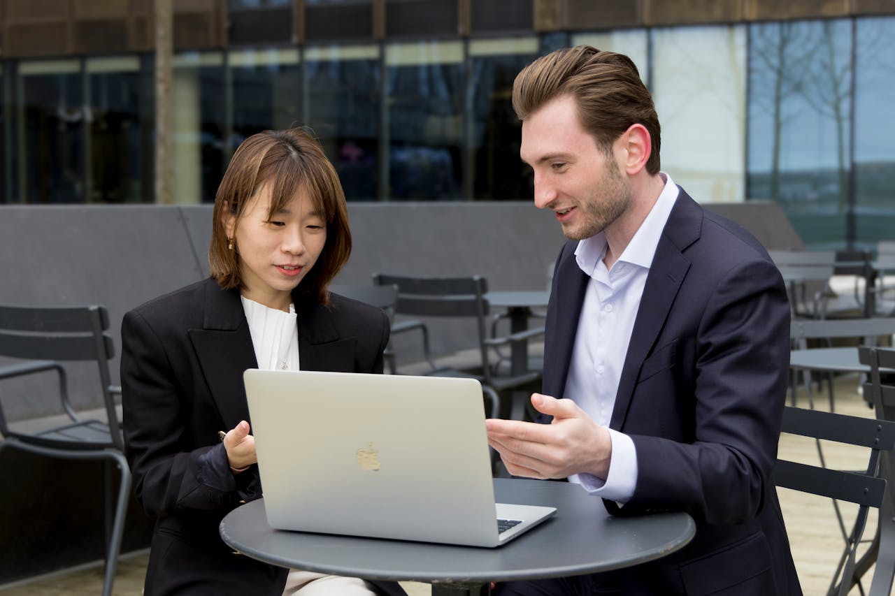 The Art of Drawing Readers In: Your attractive post title goes here Two professionals collaborating over a laptop during an outdoor business meeting.