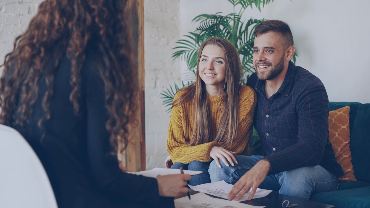 Crafting Captivating Headlines: Your awesome post title goes here Couple discussing home options with agent in modern office setting.